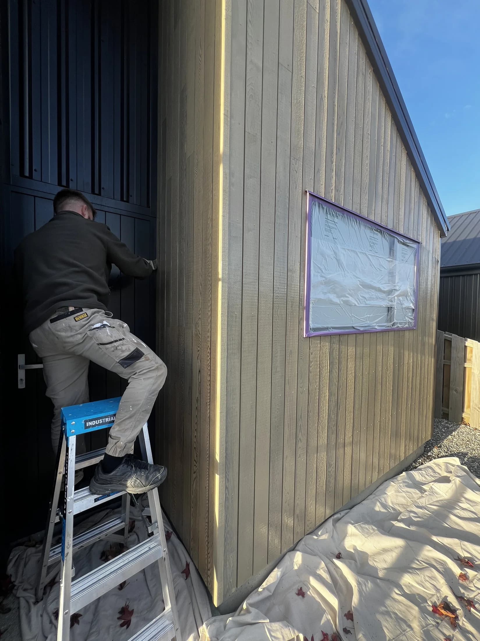 Applying cedar oil stain to weatherboards in Northlake, Wanaka