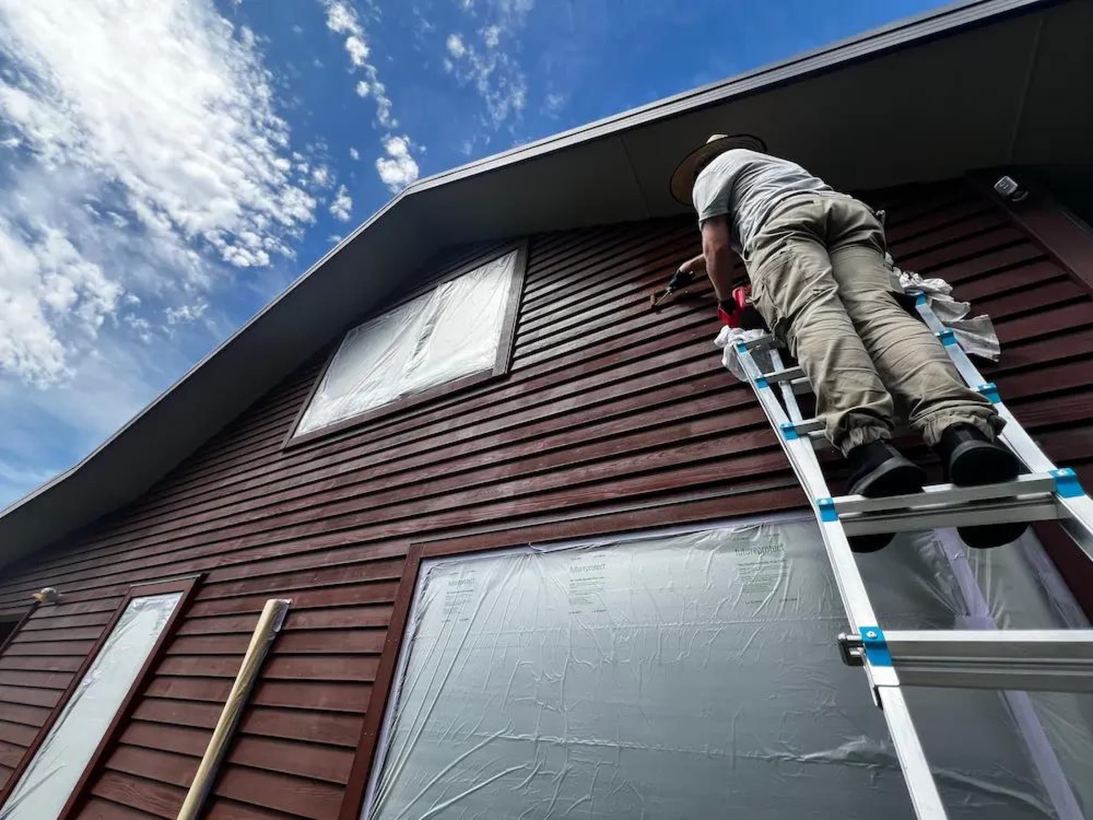 Applying cedar stain to a tall gable in Lake Hawea