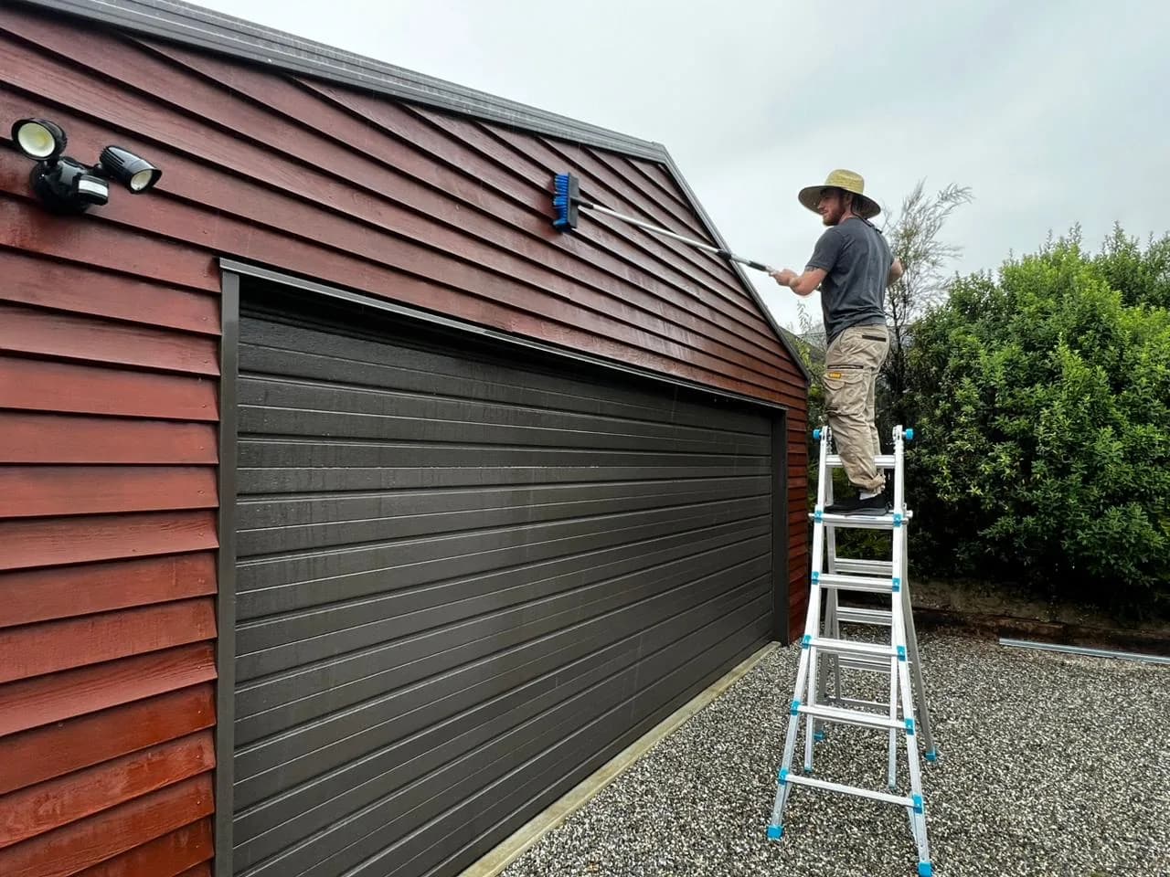 Hand washing cedar cladding with a soft brush before re-staining in Lake Hawea