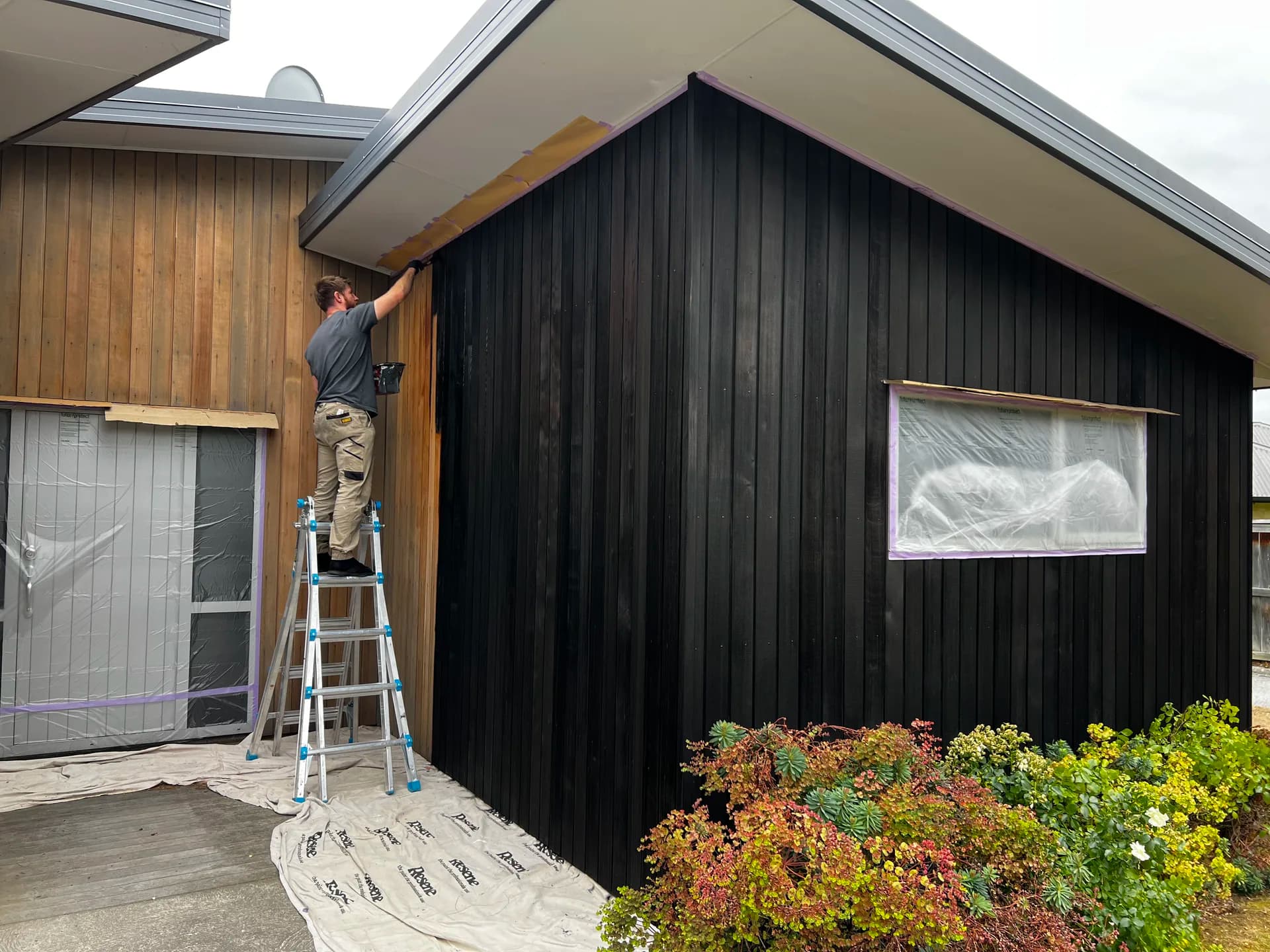 Applying cedar stain to the front exterior in Albert Town